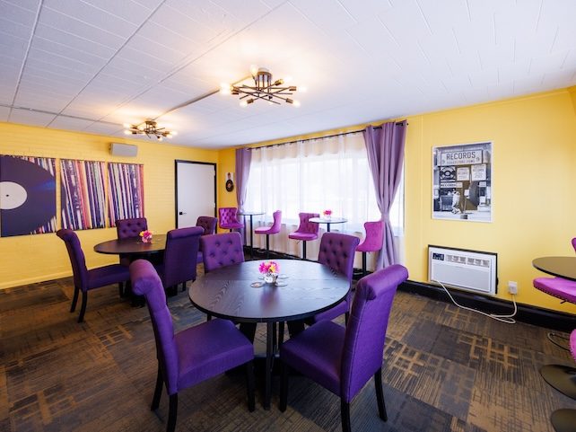 The Vinyl Room — round tables with purple velvet chairs under a sputnik chandelier
