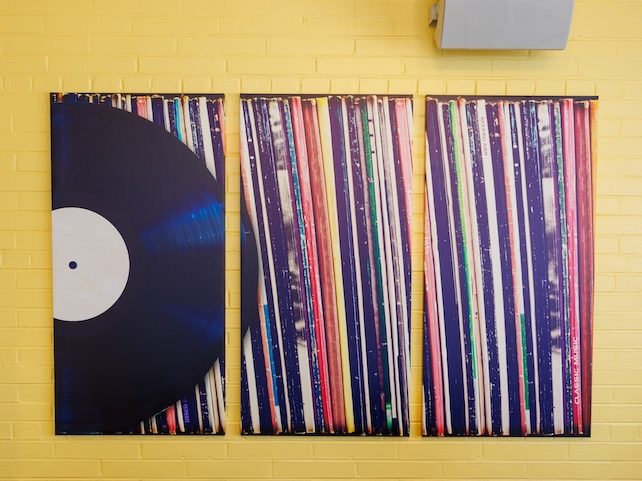 The Vinyl Room — triptych of vinyl record art on yellow brick wall