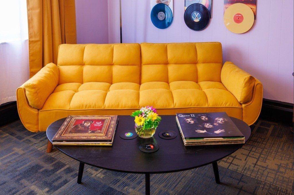 The Vinyl Room — yellow velvet sofa with three vinyl records mounted on the wall